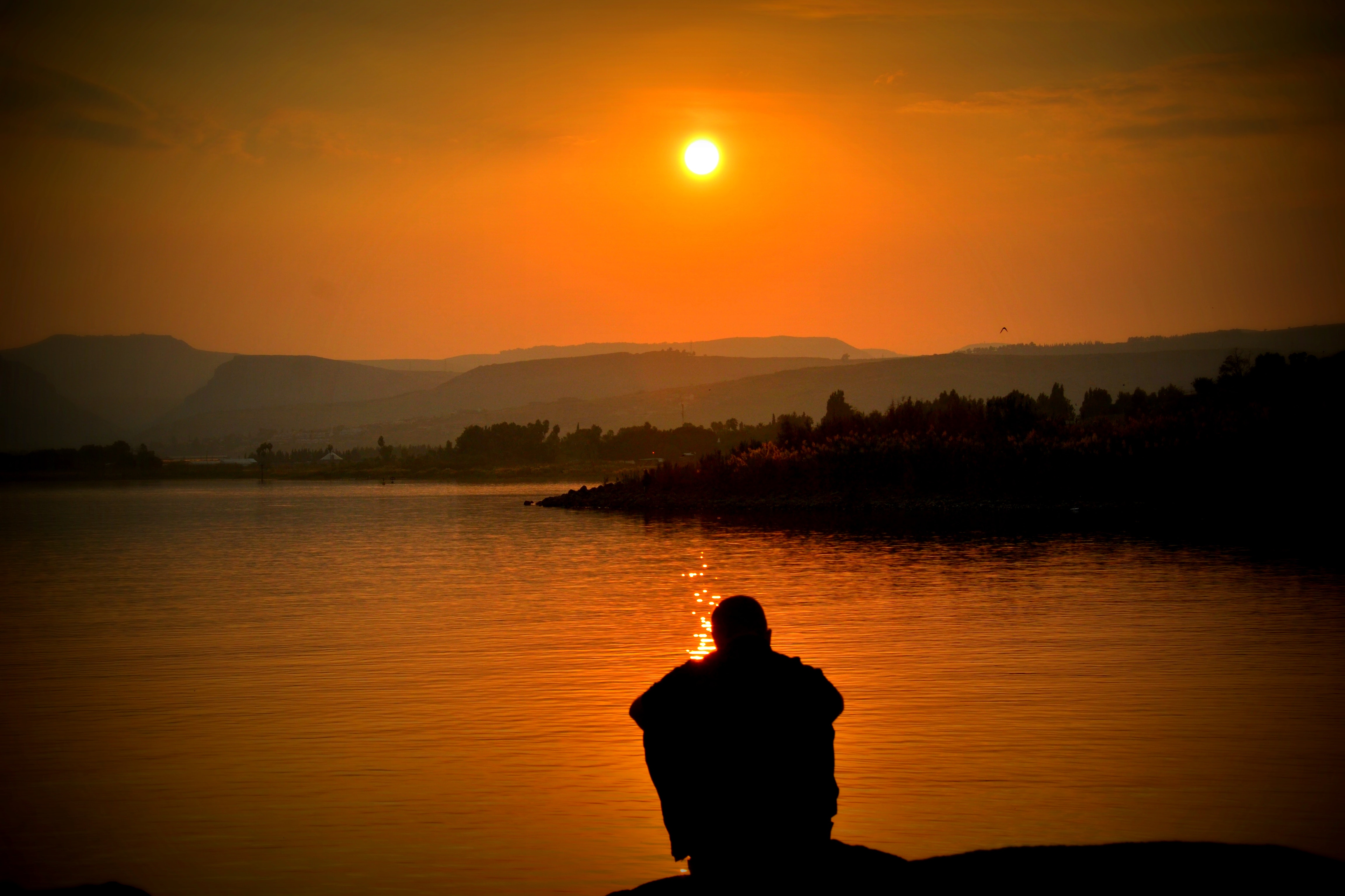 Boy in the evening in front of river and sun